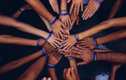 Diverse Menschen recken ihre Hände in die Mitte des Bildes