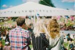 Drei Menschen, die auf ein sommerliches Festival blicken.