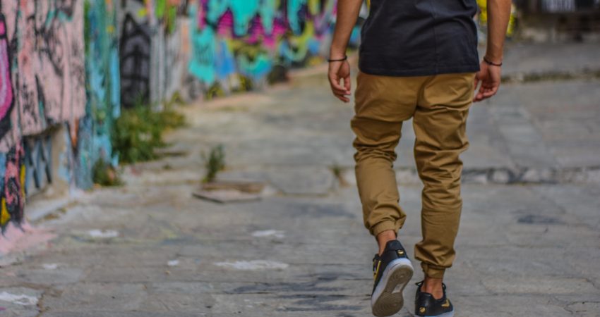 Ein Mensch läuft neben einer mit Graffiti verzierten Mauer einen Gehweg entlang