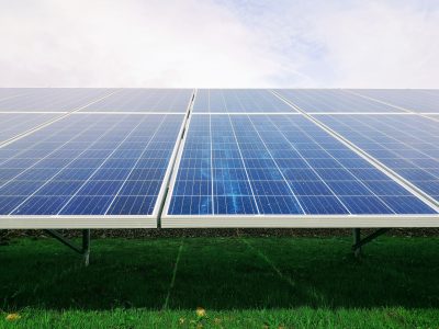 Photovoltaik-Anlge auf einer grünen Wiese im Sonnenschein, im Hintergrund freundlicher Himmel