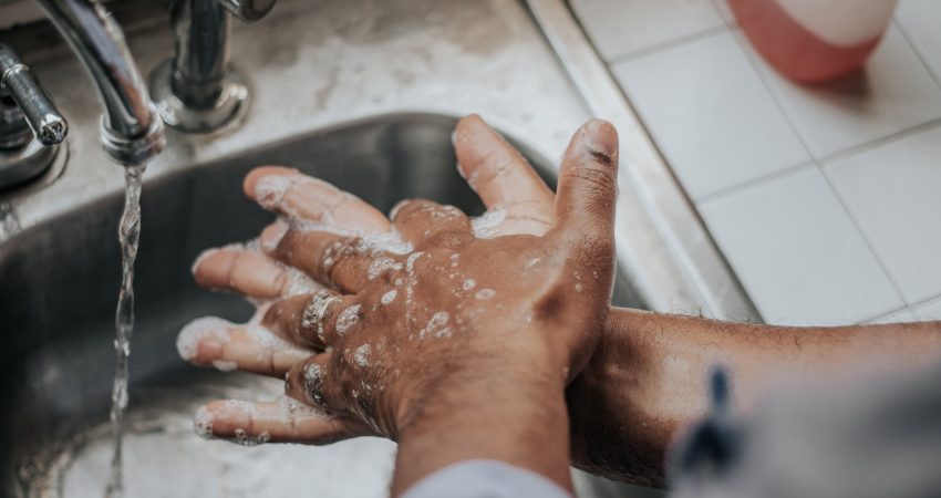 Ein Mann wäscht sich die Hände mit Seife übr einem Edelstahl-Spülbecken