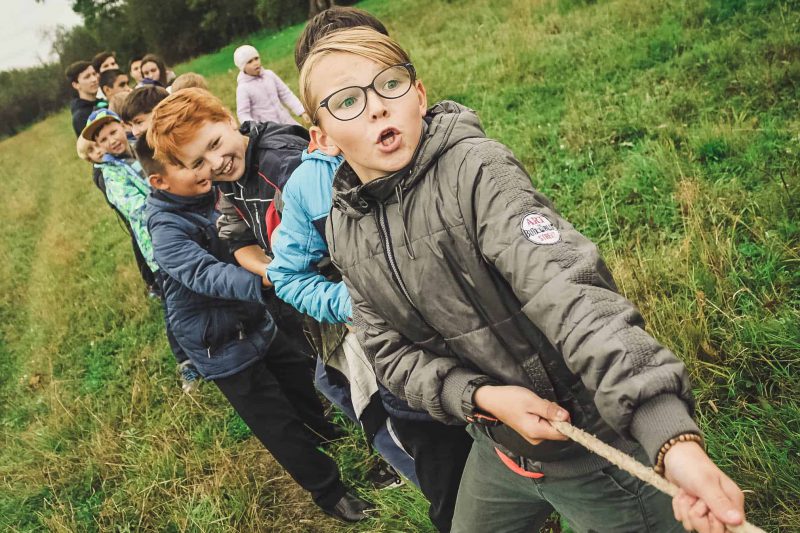 Teenager und Kinder beim Seilziehen