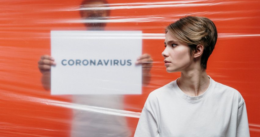 Besorgte Frau blickt auf ein Schild mit der Aufschrift "Coronavirus".