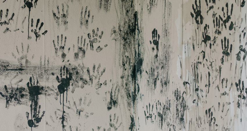 Schwarze Handabdrücke auf grauer Wand