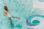 Mädchen im Schwimmbecken, das von Schwimmreifen wegschwimmt