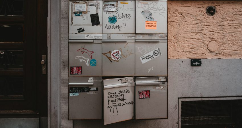 Briefkastenblock mit 9 Briefkästen, die Aufkleber und Schmierereien tragen
