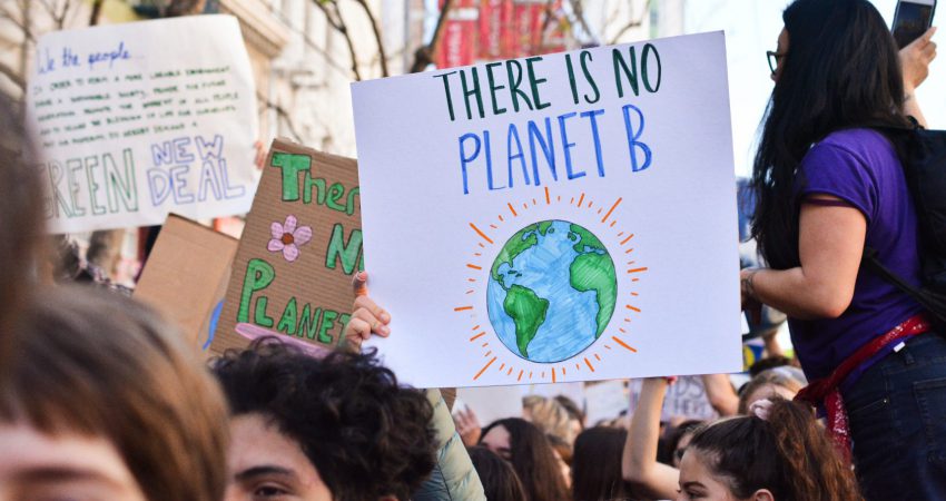 Demonstrierende, die ein Plakat mit der Aufschrift "There ist no Planet B" hochhalten.