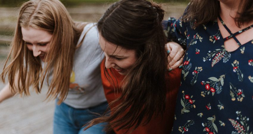 Drei junge Frauen, die sich lachend umarmen