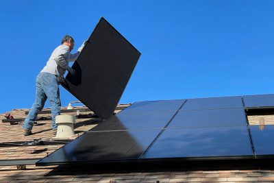 Mann montiert Solaranlage auf einem Dach.