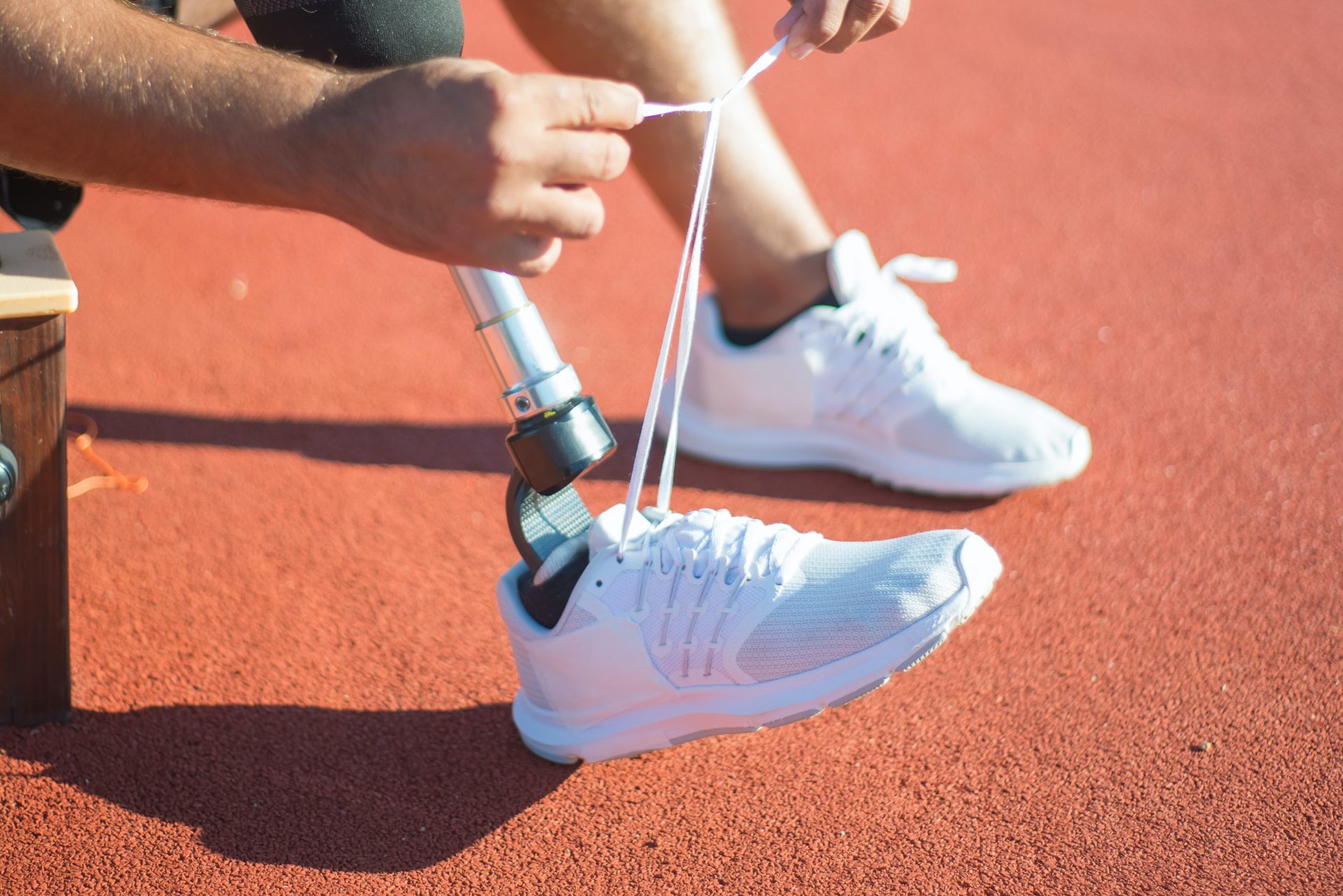 ein Parasportler mit Beinprothese bindet sich die Schuhe zu