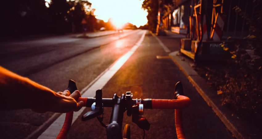 Fahrradfahrer:in auf Rennrad fährt in Sonnenuntergang