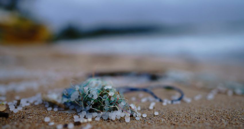 Plastik und Plastikkugeln in Großaufnahme im Sand