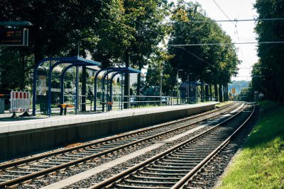 Blick auf eine Haltestelle (Zug/S-Bahn), gesäumt von Laubbäumen