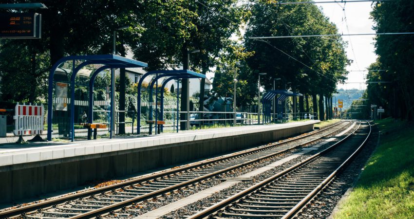 Blick auf eine Haltestelle (Zug/S-Bahn), gesäumt von Laubbäumen