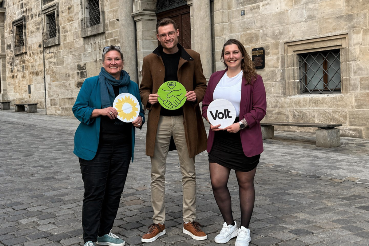 Andrea Friedel, Alex Kahl von der grünen Stadtratsfraktion Nürnberg und Isaura Süssner von Volt stehen vorm Alten Rathaus und lächeln in die Kamera