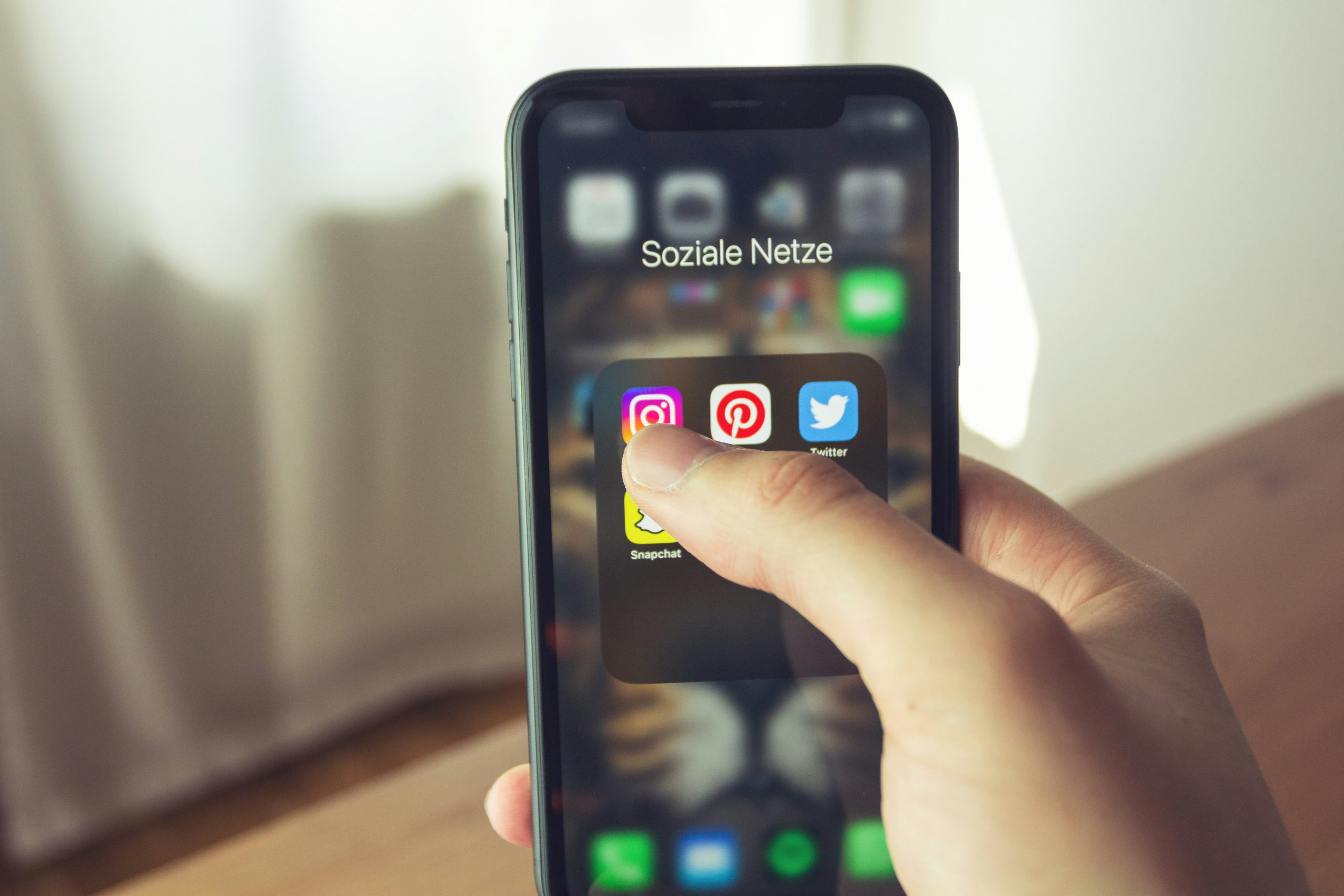 Smartphone mit Social-Media-Apps , das in einer Hand liegt, der Daumen tippt auf die Instagram-App