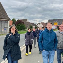 Mehrere Menschen wandern vor dörflichem Hintergrund. Britta Walthelm